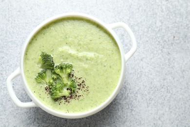 Photo of Delicious broccoli cream soup in bowl on light table, top view