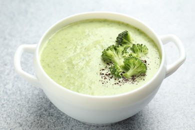 Photo of Delicious broccoli cream soup in bowl on light table, closeup