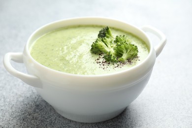 Photo of Delicious broccoli cream soup in bowl on light table, closeup