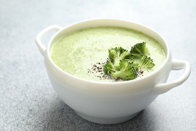 Photo of Delicious broccoli cream soup in bowl on light table, closeup