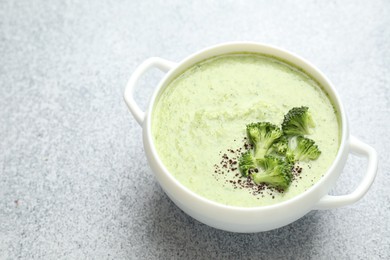 Photo of Delicious broccoli cream soup in bowl on light table, closeup