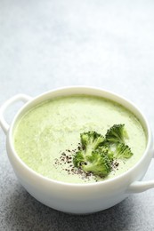 Photo of Delicious broccoli cream soup in bowl on light table, closeup