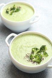 Photo of Delicious broccoli cream soup in bowls on light table, closeup