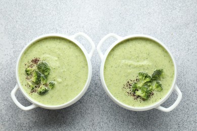 Photo of Delicious broccoli cream soup in bowls on light table, top view