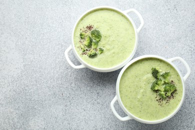 Photo of Delicious broccoli cream soup in bowls on light table, top view. Space for text