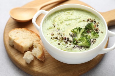 Photo of Delicious broccoli cream soup served on light table, closeup