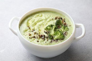 Photo of Delicious broccoli cream soup in bowl on light table, closeup