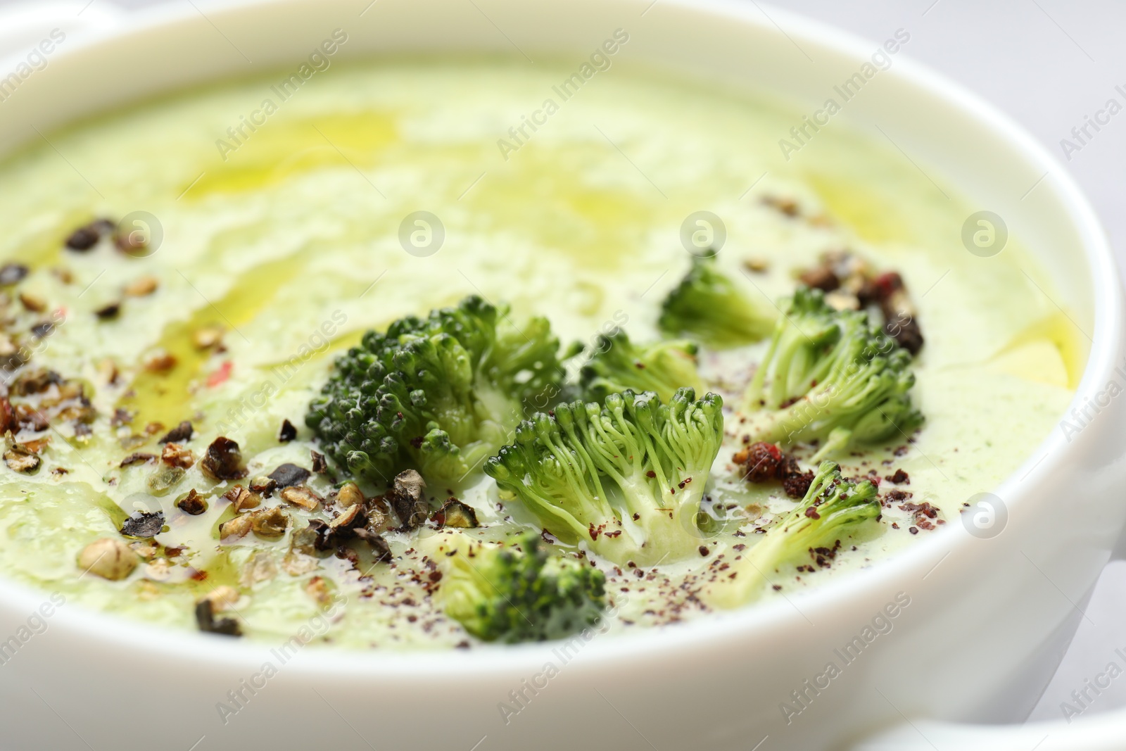 Photo of Delicious broccoli cream soup in bowl on light table, closeup