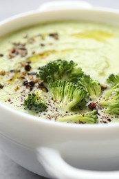 Photo of Delicious broccoli cream soup in bowl on light table, closeup