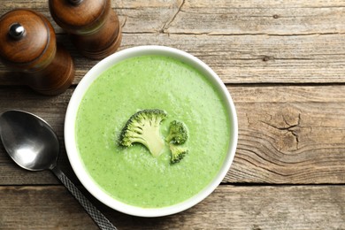 Photo of Delicious broccoli cream soup served on wooden table, top view. Space for text