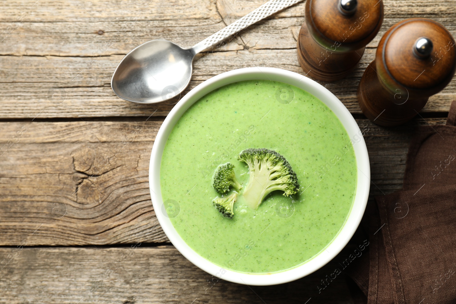 Photo of Delicious broccoli cream soup served on wooden table, top view. Space for text