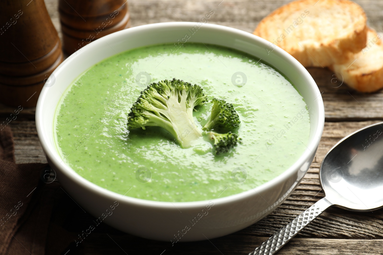 Photo of Delicious broccoli cream soup served on wooden table, closeup