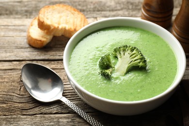 Photo of Delicious broccoli cream soup served on wooden table, closeup