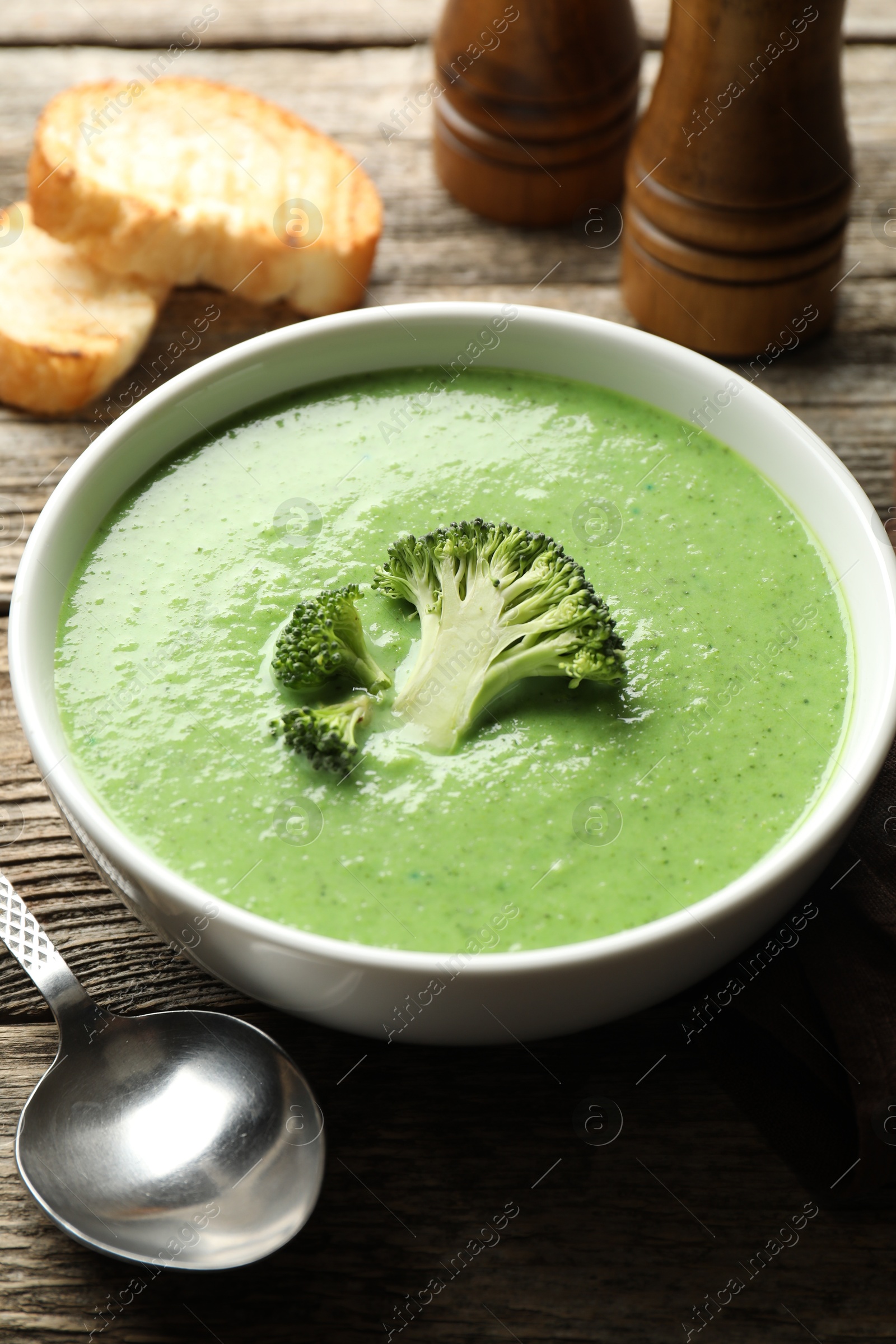 Photo of Delicious broccoli cream soup served on wooden table, closeup