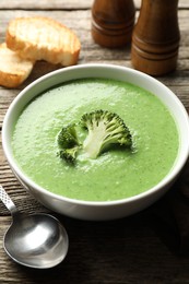 Photo of Delicious broccoli cream soup served on wooden table, closeup