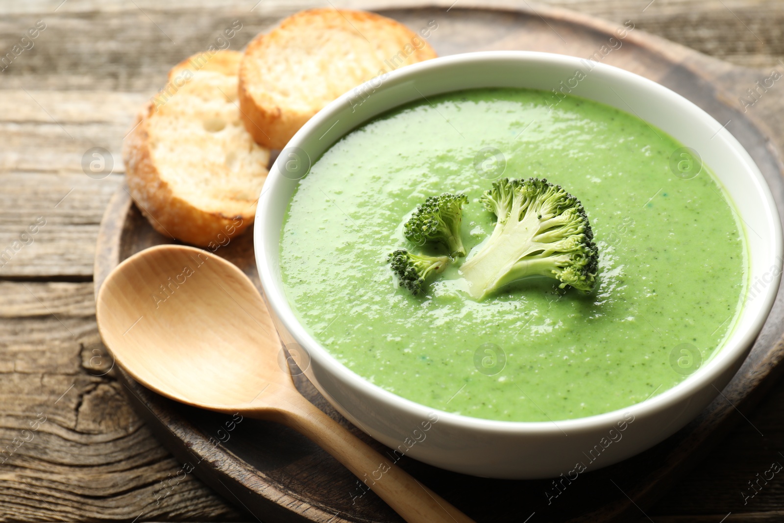 Photo of Delicious broccoli cream soup served on wooden table, closeup