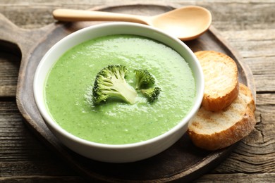 Photo of Delicious broccoli cream soup served on wooden table, closeup