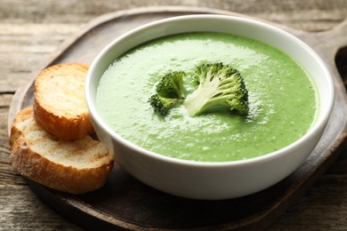 Photo of Delicious broccoli cream soup served on wooden table, closeup