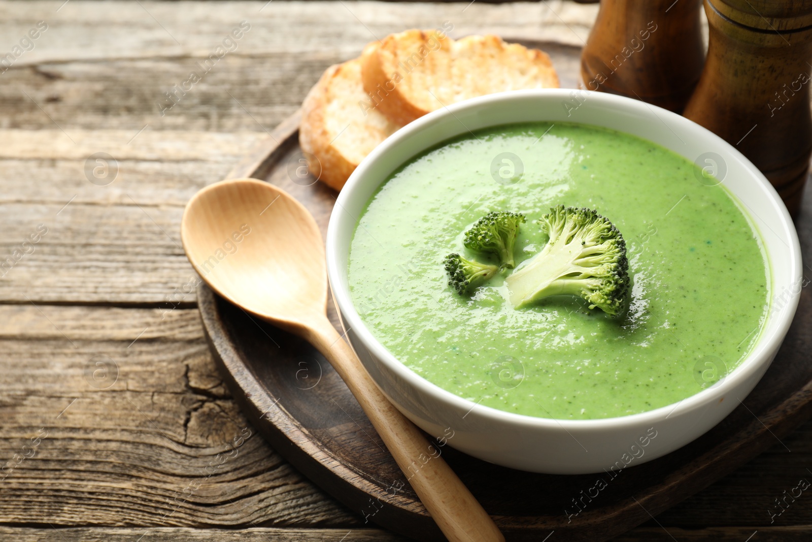 Photo of Delicious broccoli cream soup served on wooden table, closeup