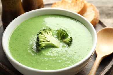 Photo of Delicious broccoli cream soup served on wooden table, closeup