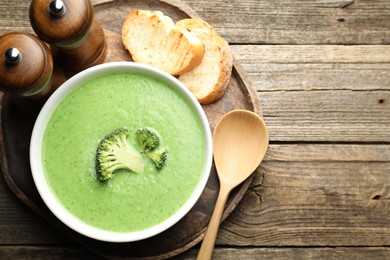 Photo of Delicious broccoli cream soup served on wooden table, top view. Space for text