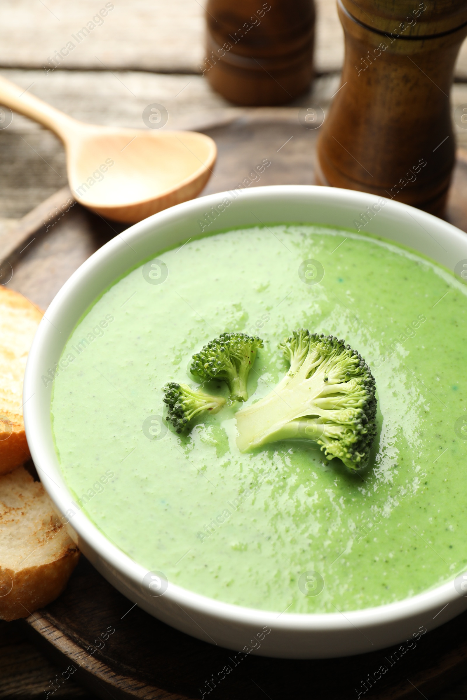 Photo of Delicious broccoli cream soup served on wooden table, closeup