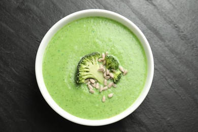 Photo of Delicious broccoli cream soup in bowl on black table, top view