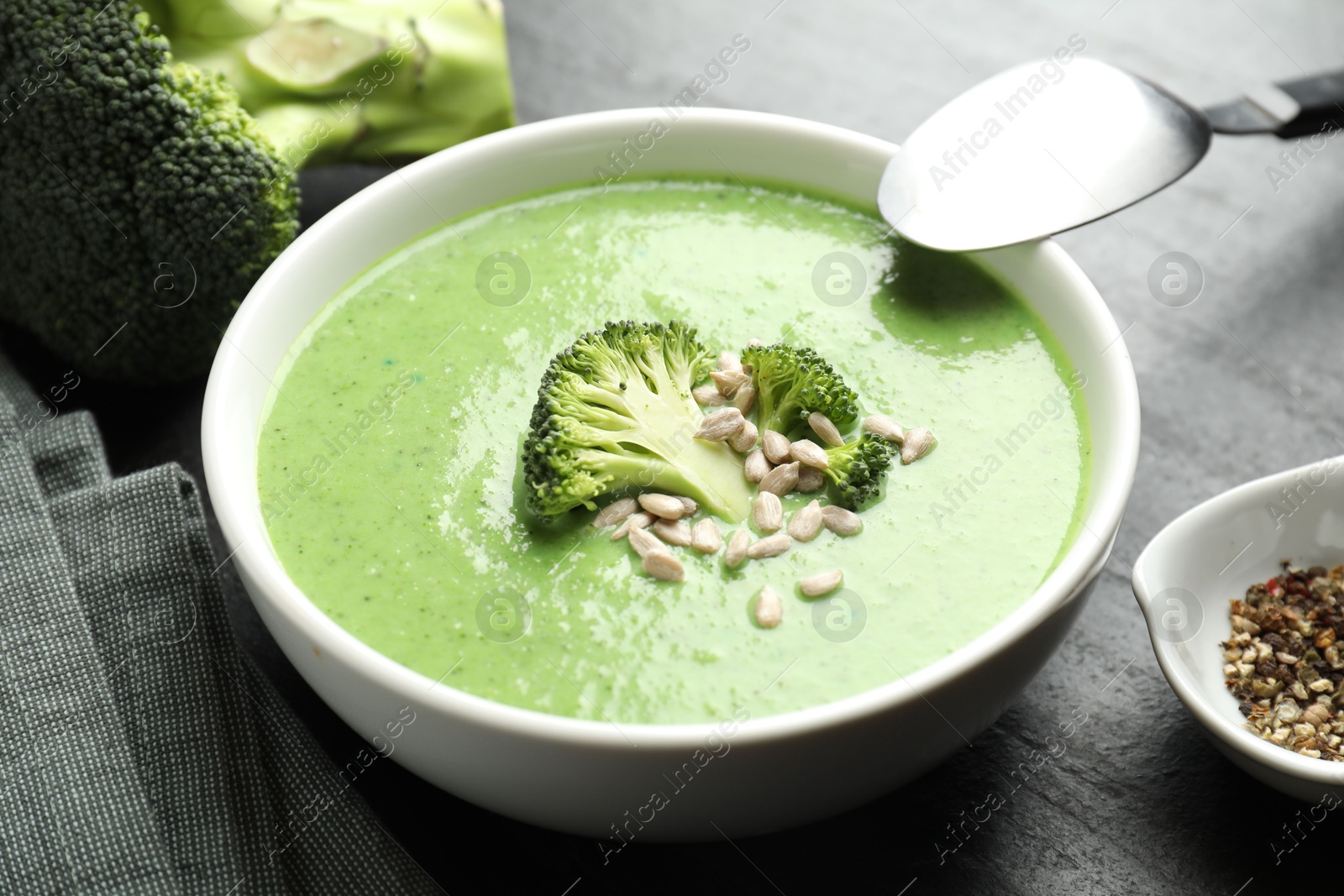 Photo of Delicious broccoli cream soup served on black table, closeup