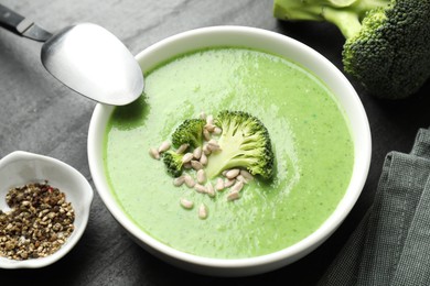 Photo of Delicious broccoli cream soup served on black table, closeup