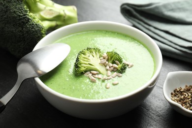 Photo of Delicious broccoli cream soup served on black table, closeup