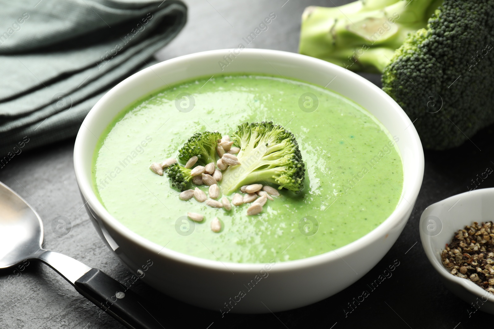 Photo of Delicious broccoli cream soup served on black table, closeup