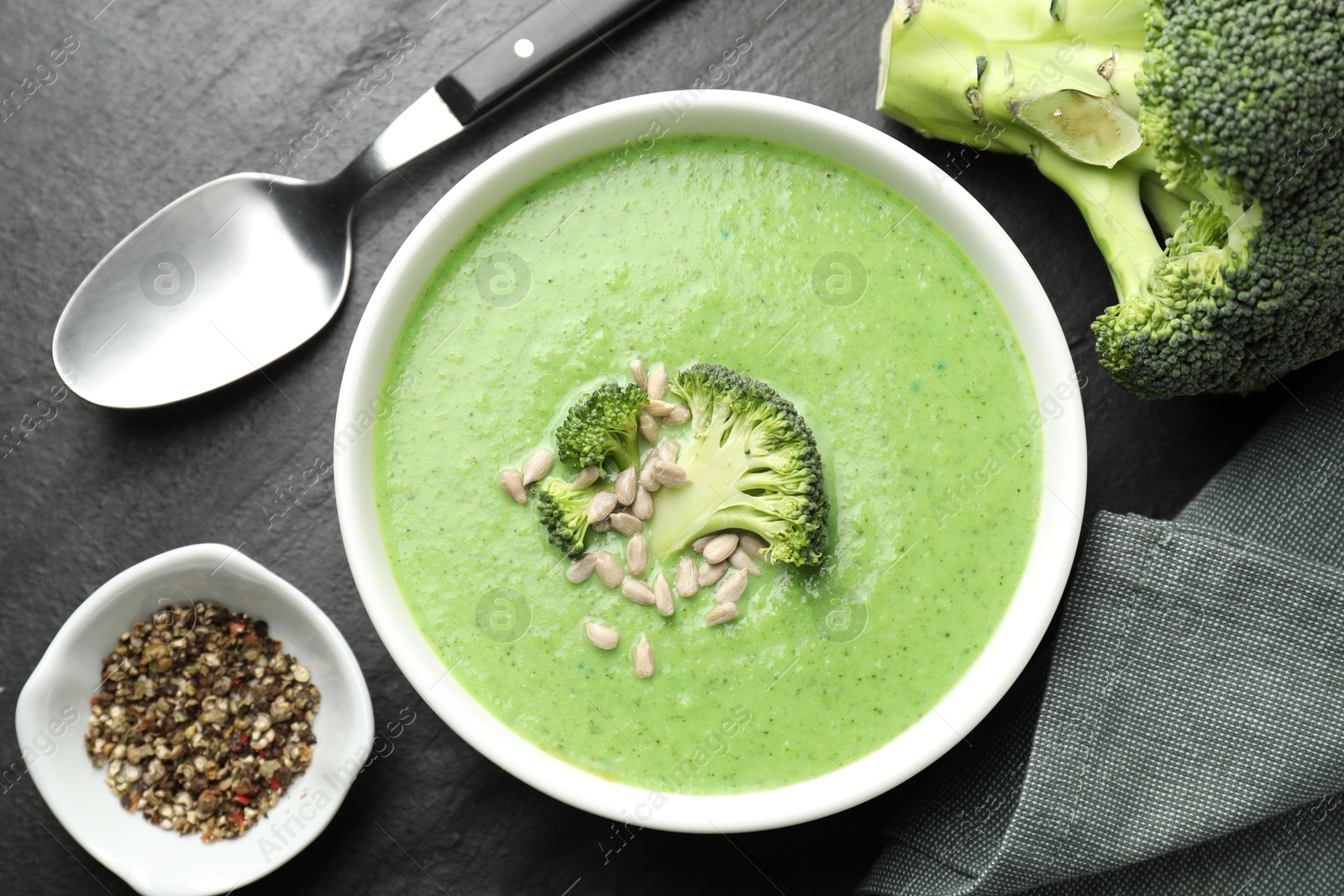 Photo of Delicious broccoli cream soup served on black table, flat lay