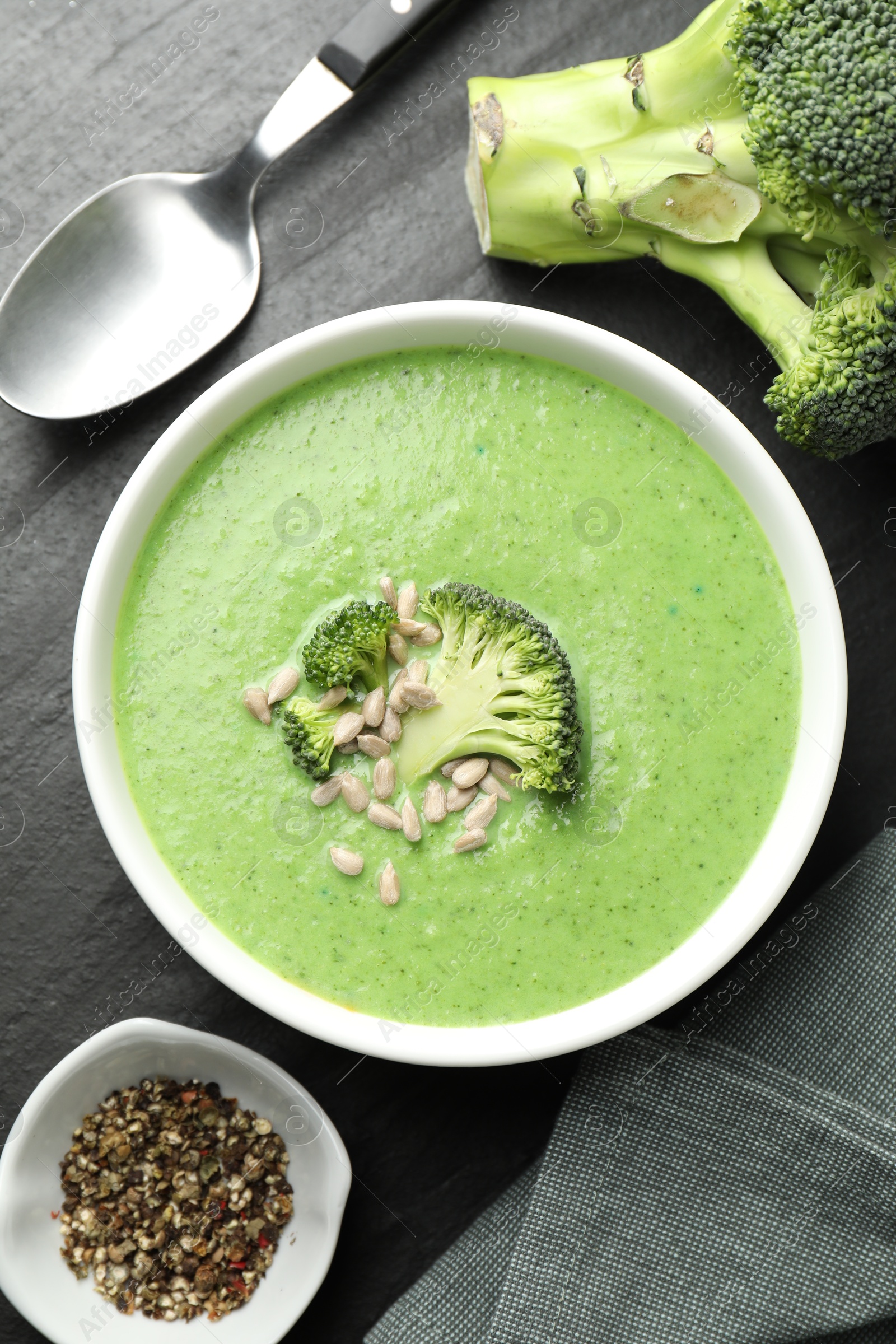 Photo of Delicious broccoli cream soup served on black table, flat lay