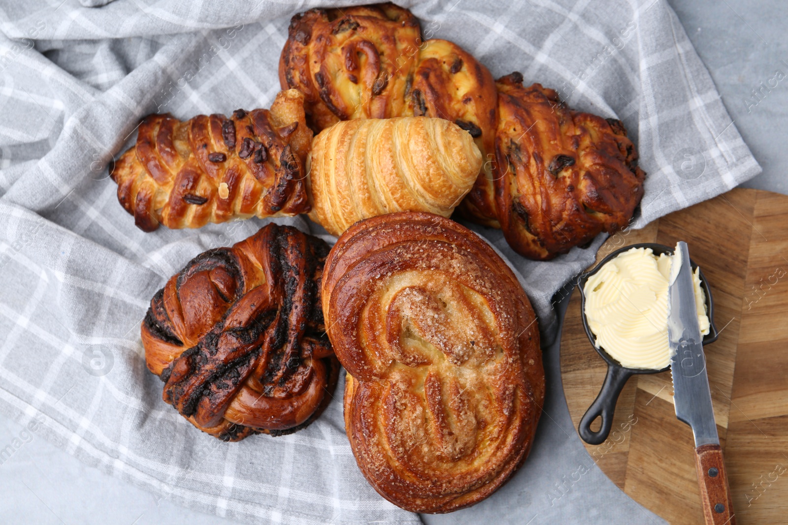 Photo of Different delicious pastries, butter and knife on grey table, top view