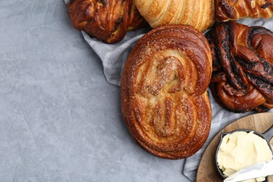 Photo of Different delicious pastries and butter on grey table, top view. Space for text