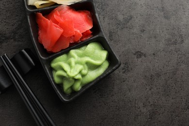 Photo of Hot wasabi paste, ginger and chopsticks on grey table, top view. Space for text