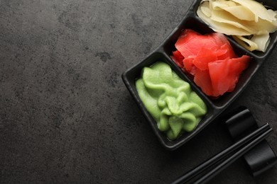 Photo of Hot wasabi paste, ginger and chopsticks on grey table, top view. Space for text