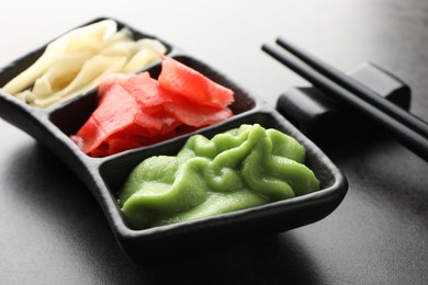 Photo of Hot wasabi paste, ginger and chopsticks on grey table, closeup