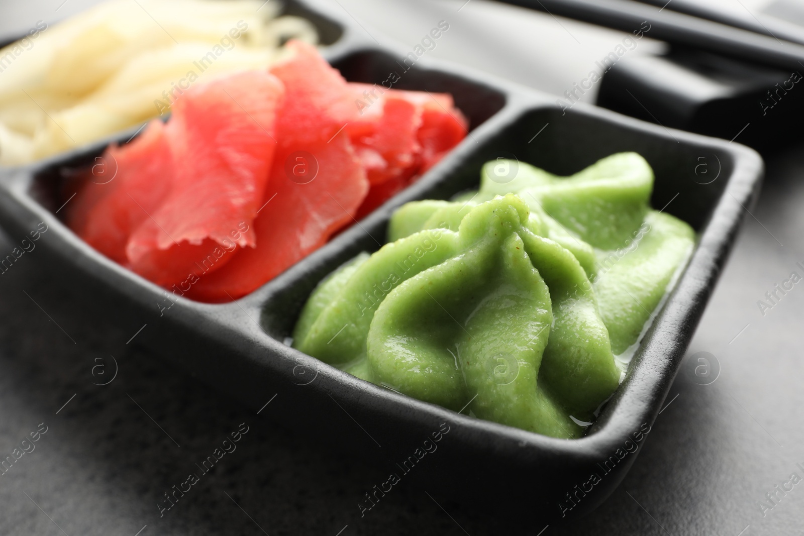 Photo of Hot wasabi paste and ginger on grey table, closeup