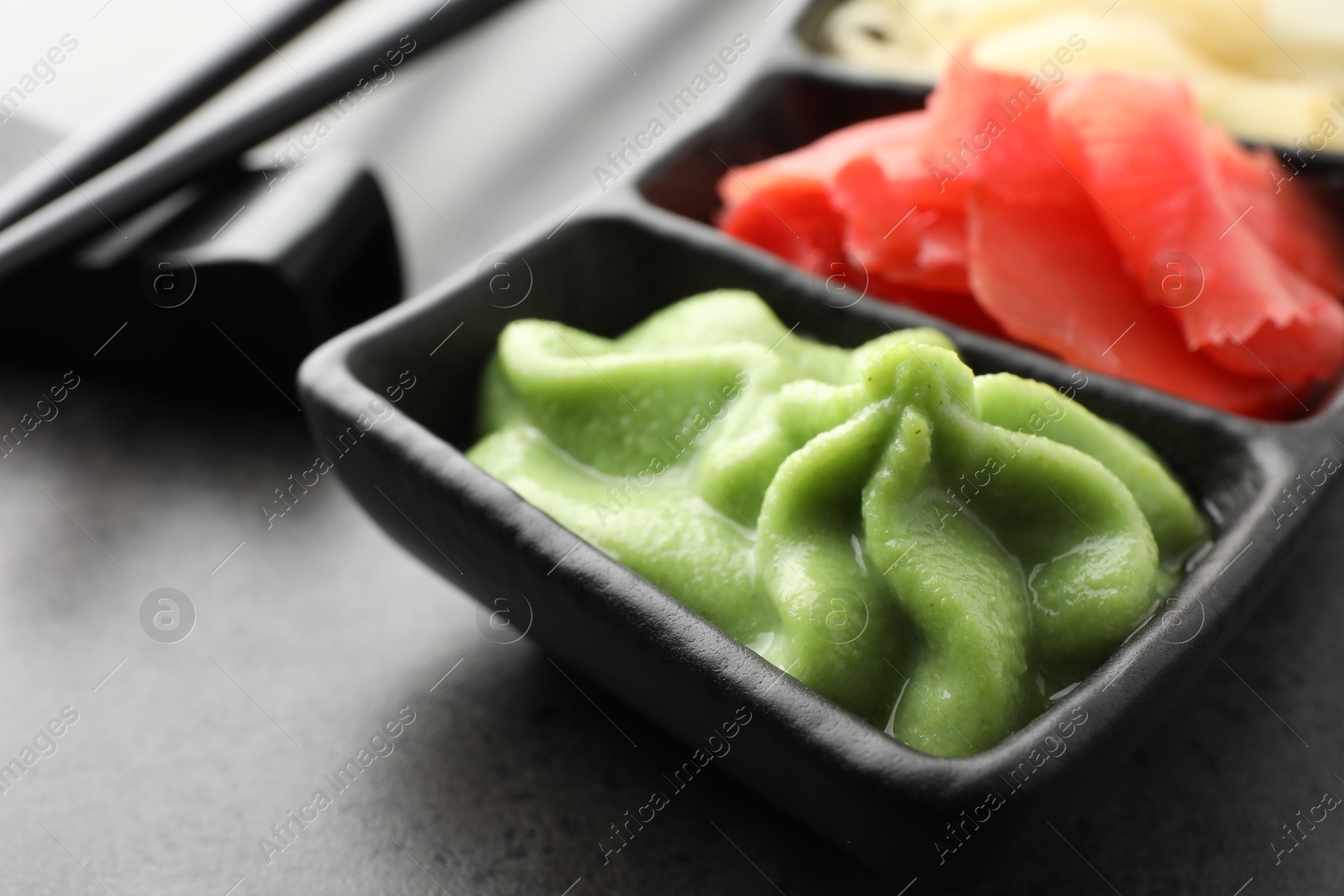 Photo of Hot wasabi paste and ginger on grey table, closeup