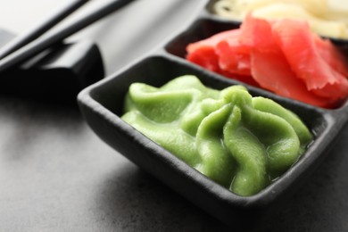 Photo of Hot wasabi paste and ginger on grey table, closeup