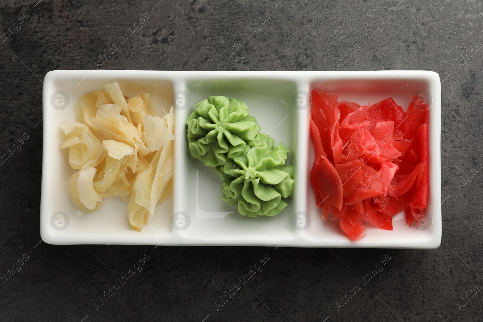 Photo of Hot wasabi paste and ginger on grey table, top view