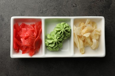 Photo of Hot wasabi paste and ginger on grey table, top view