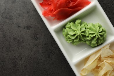 Photo of Hot wasabi paste and ginger on grey table, top view. Space for text