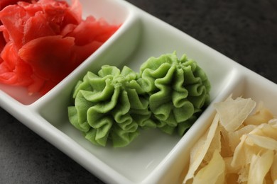 Photo of Hot wasabi paste and ginger on grey table, closeup