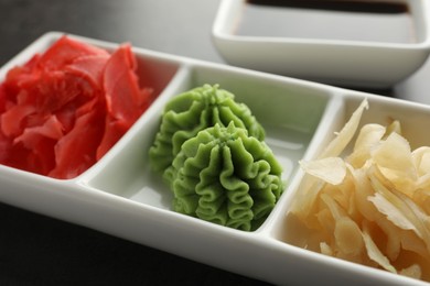 Photo of Hot wasabi paste and ginger on grey table, closeup