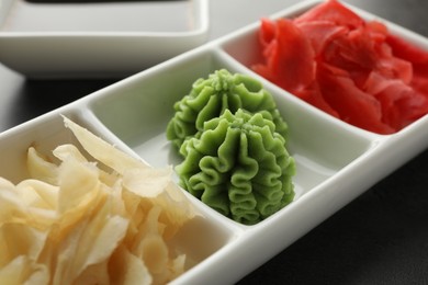 Photo of Hot wasabi paste and ginger on grey table, closeup