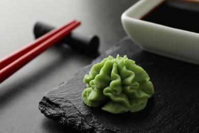 Photo of Hot wasabi paste, soy sauce and chopsticks on grey table, closeup