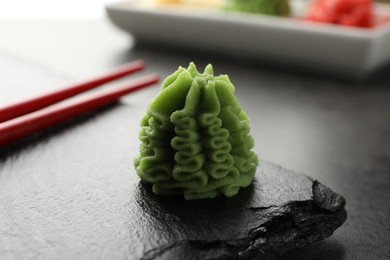 Photo of Hot wasabi paste and chopsticks on grey table, closeup