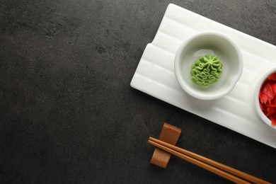 Photo of Hot wasabi paste, ginger and chopsticks on grey table, top view. Space for text